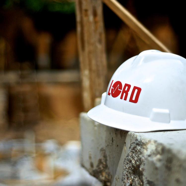 White hard hat with Lord logo on a tabletop at a construction site