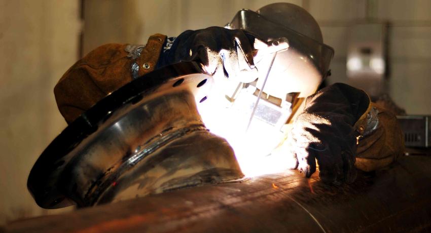 Welder working on industrial piping