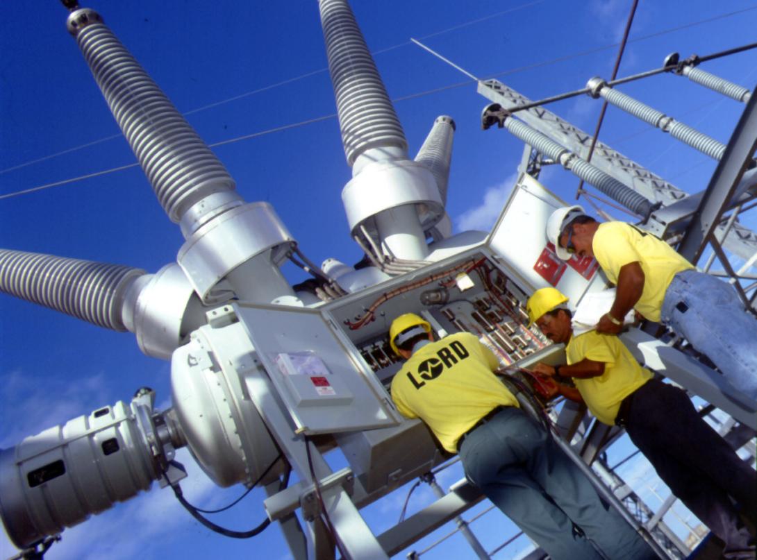 Three electrical workers with industrial transformer